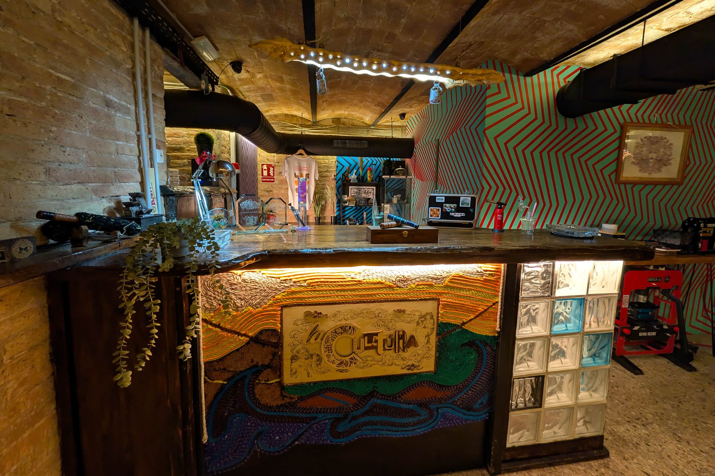 Bar area of the cannabis club La Cultura with artistic counter and vibrant wall design in Barcelona
